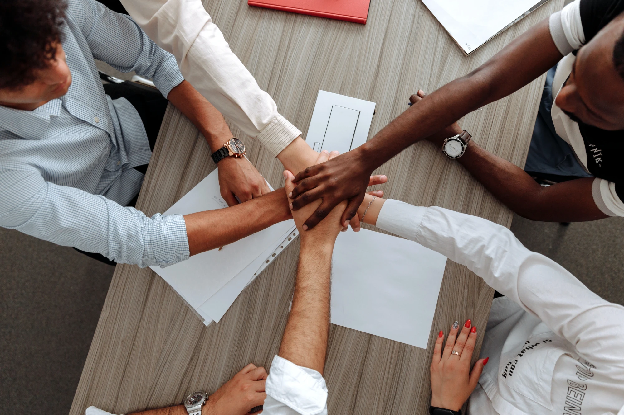 Team joining hands over a table of documents