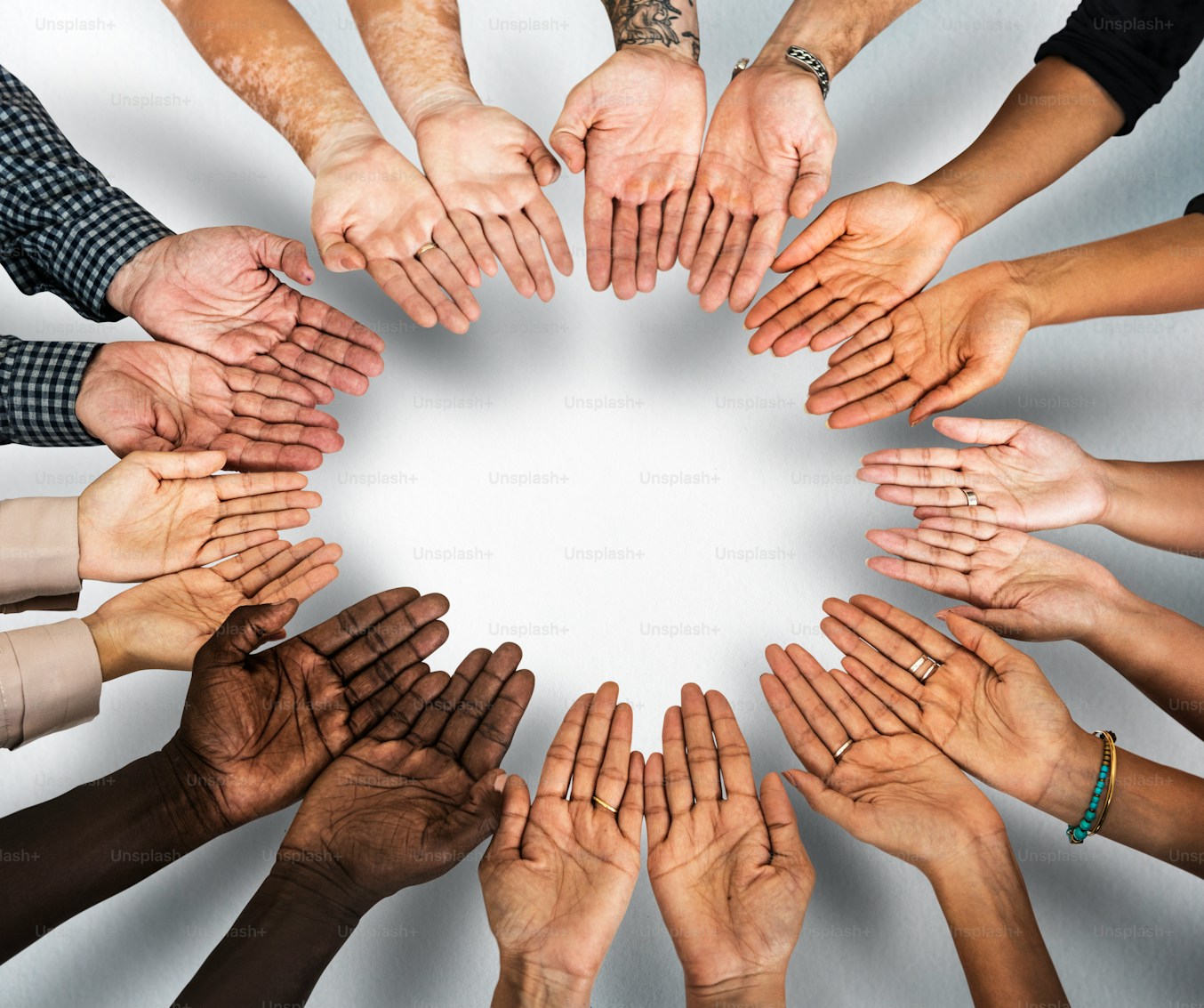 A diverse group of people placing their open hands together in a circle